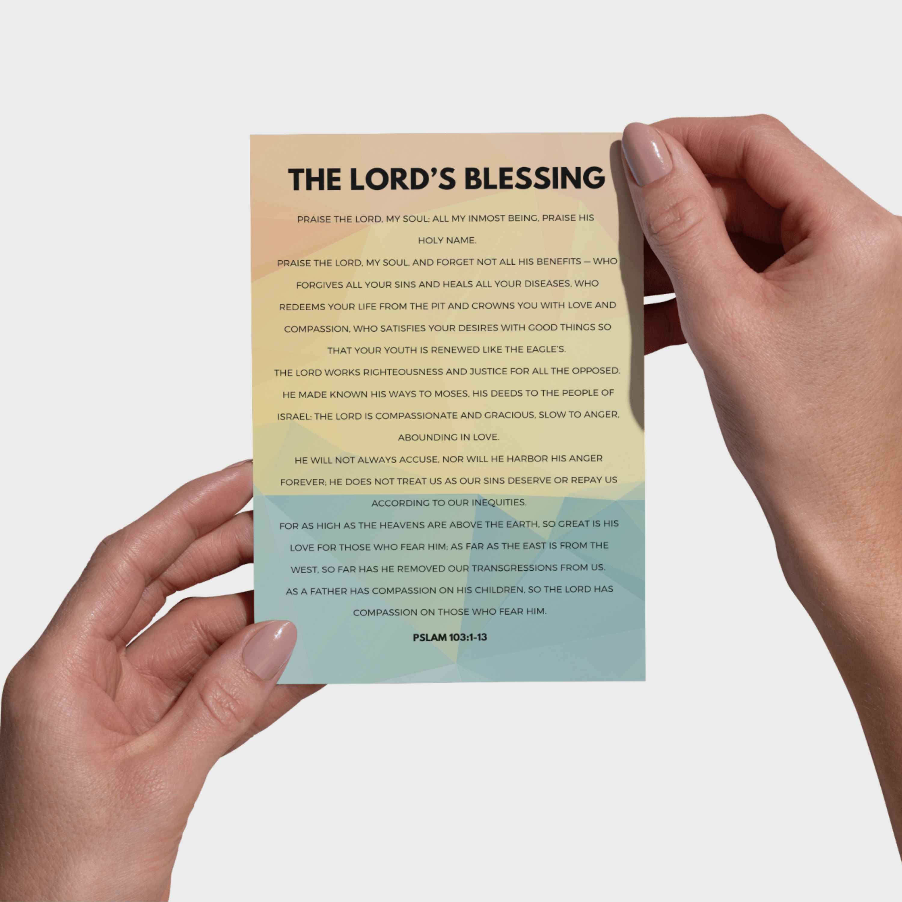 Hands holding a 5x7 print with 'The Lord's Blessing' text and gradient design, on a light background