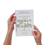 Hands holding the book Your Journey From Broken To Blessed: Finding the Love You Didn't Receive by Dr. John Trent and Kari Trent Stageberg, with a tan cover and a green plant with roots growing through the words