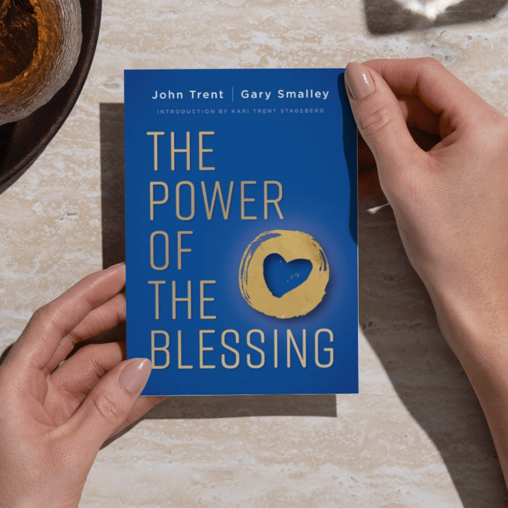 Book titled 'The Power of the Blessing' held by a person on a light surface.