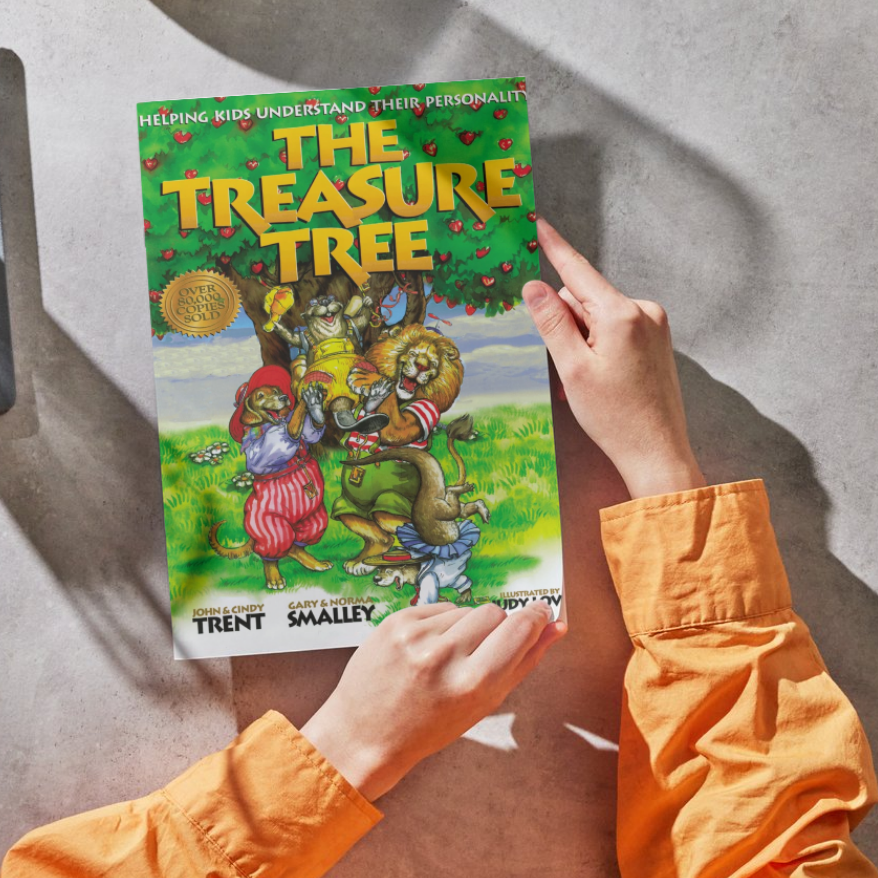 person with an orange shirt holding The Treasure Tree book
