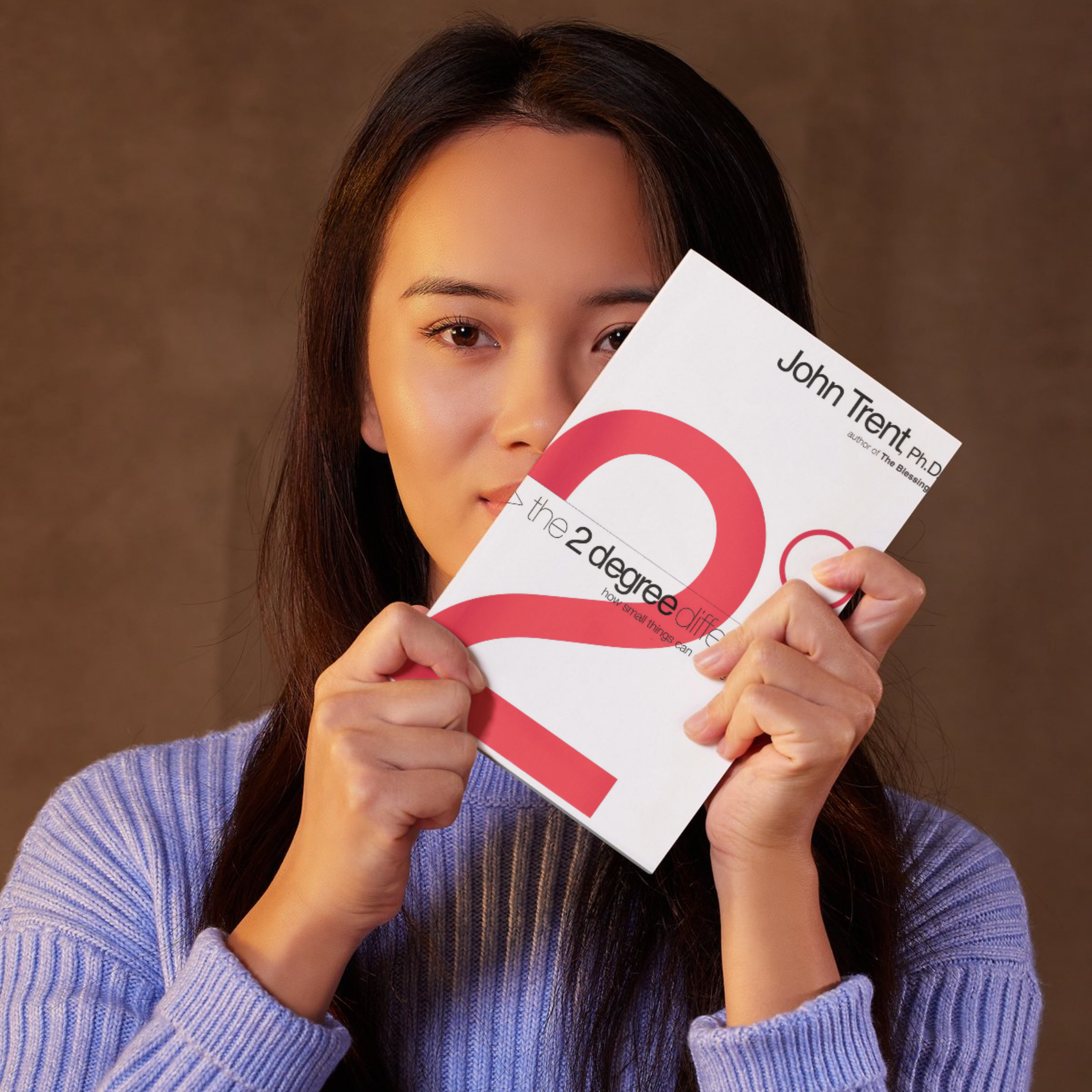 The cover of the book 'The Two Degree Difference' by John Trent, featuring a red and white design with the title and author's name being held by a woman with dark hair and a purple sweater