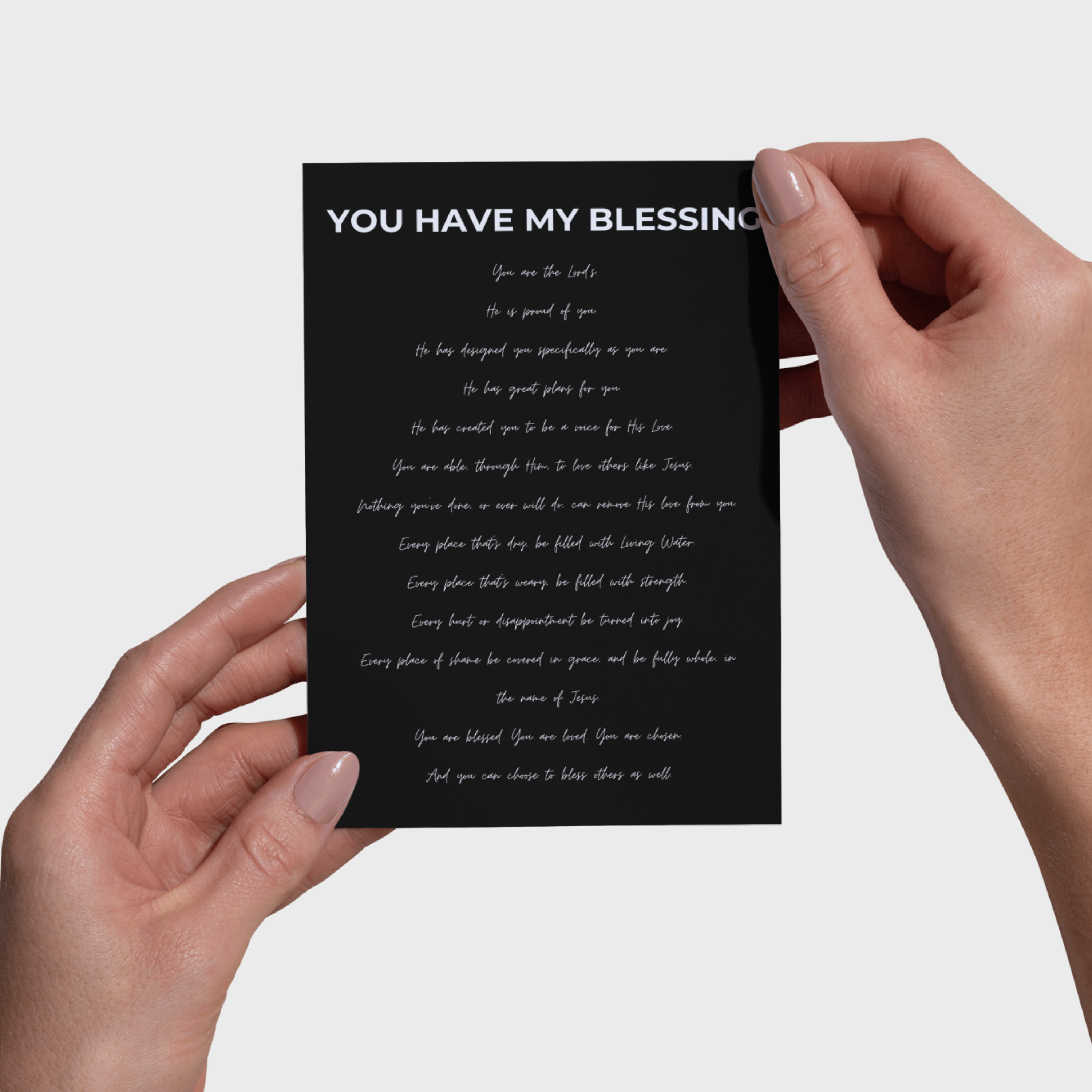 Hands holding a black 5x7 print with white text against a light gray background